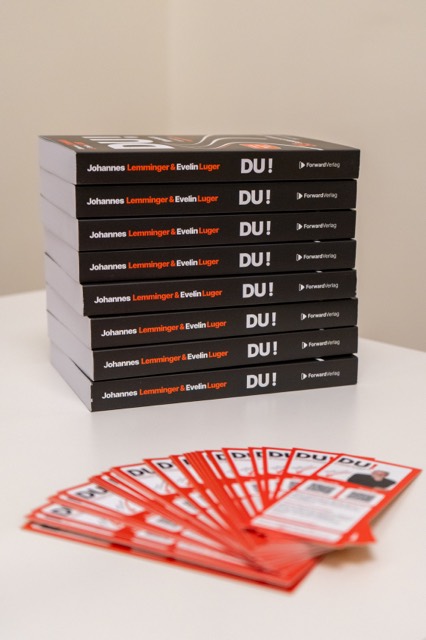 Gestapelte Exemplare des Buches DU! mit Flyern