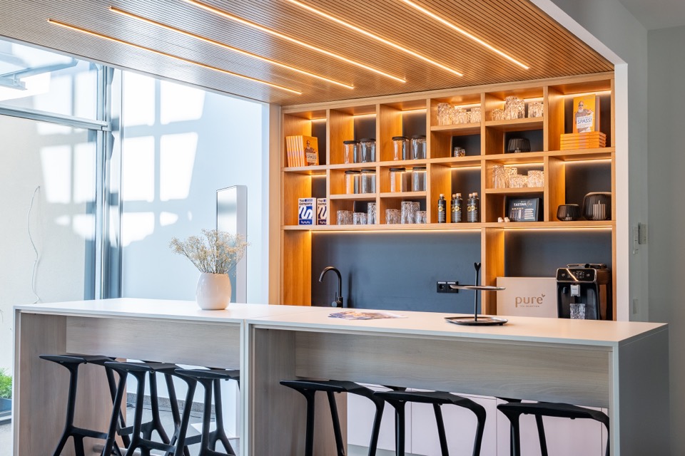 Kaffeebar mit beleuchtetem Holzregal und Barhockern