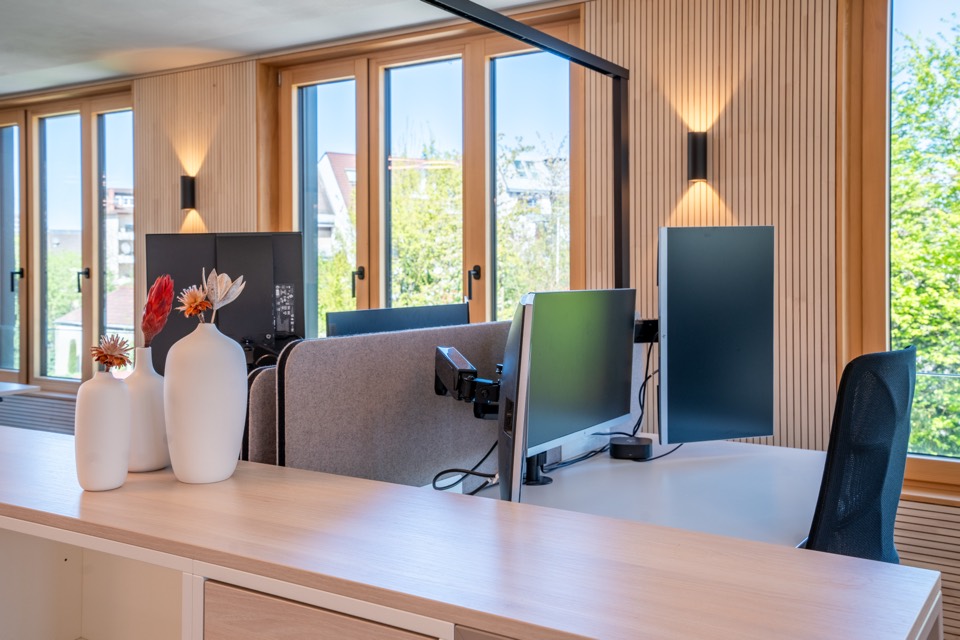 Arbeitsplatz mit Monitor und Blumen am Fenster