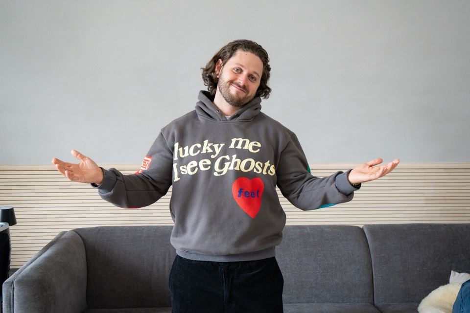 Teilnehmer im Hoodie breitet lachend die Arme aus