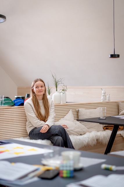 Teilnehmerin sitzt lächelnd auf der Fensterbank