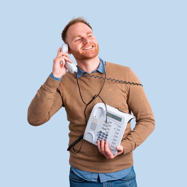 Mann lacht am Telefonhörer vor blauem Hintergrund