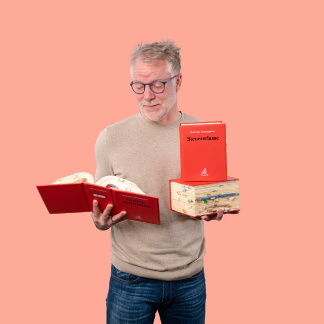 Mann mit aufgeschlagenem Gesetzbuch vor korallenrotem Hintergrund