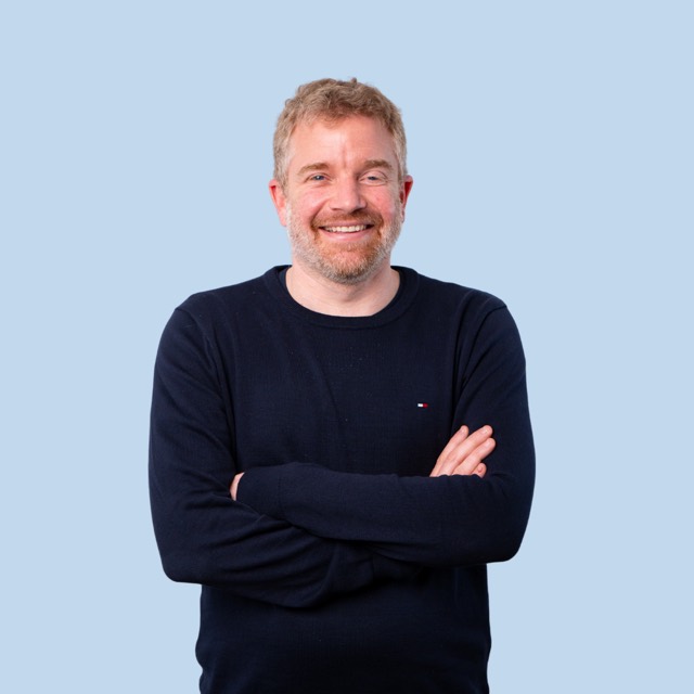 Mann im dunklen Pullover vor blauem Hintergrund