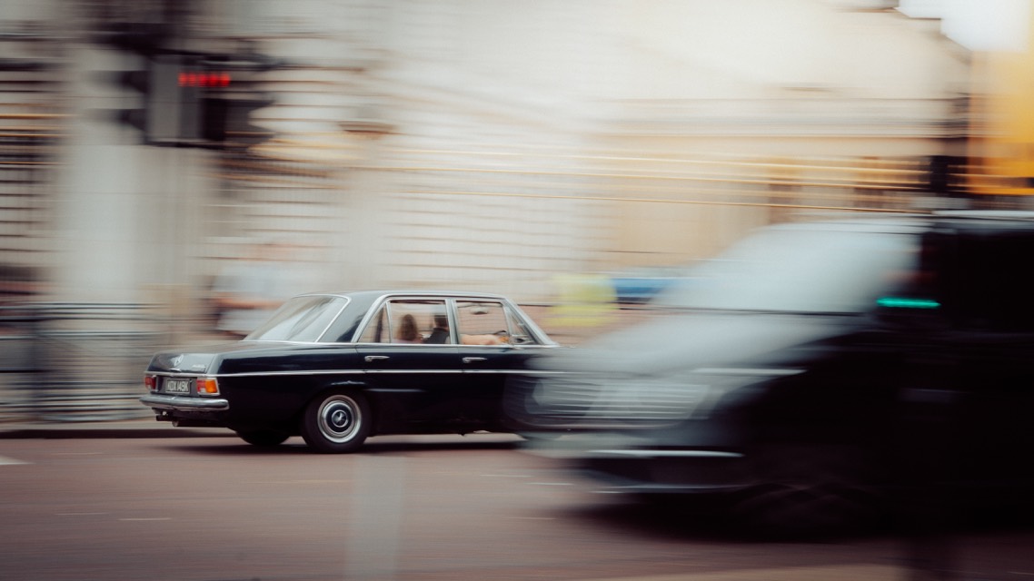 Alter Mercedes im Mitzieher, Hintergrund verwischt